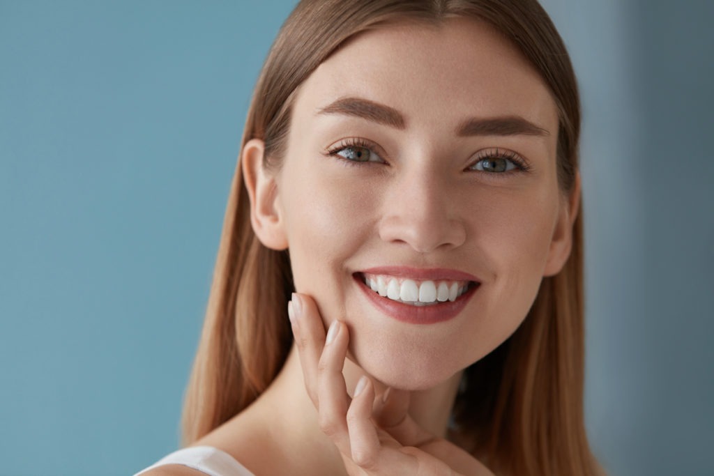Smiling young woman with straight teeth showcasing the benefits of braces and orthodontic treatment in Virginia Beach.